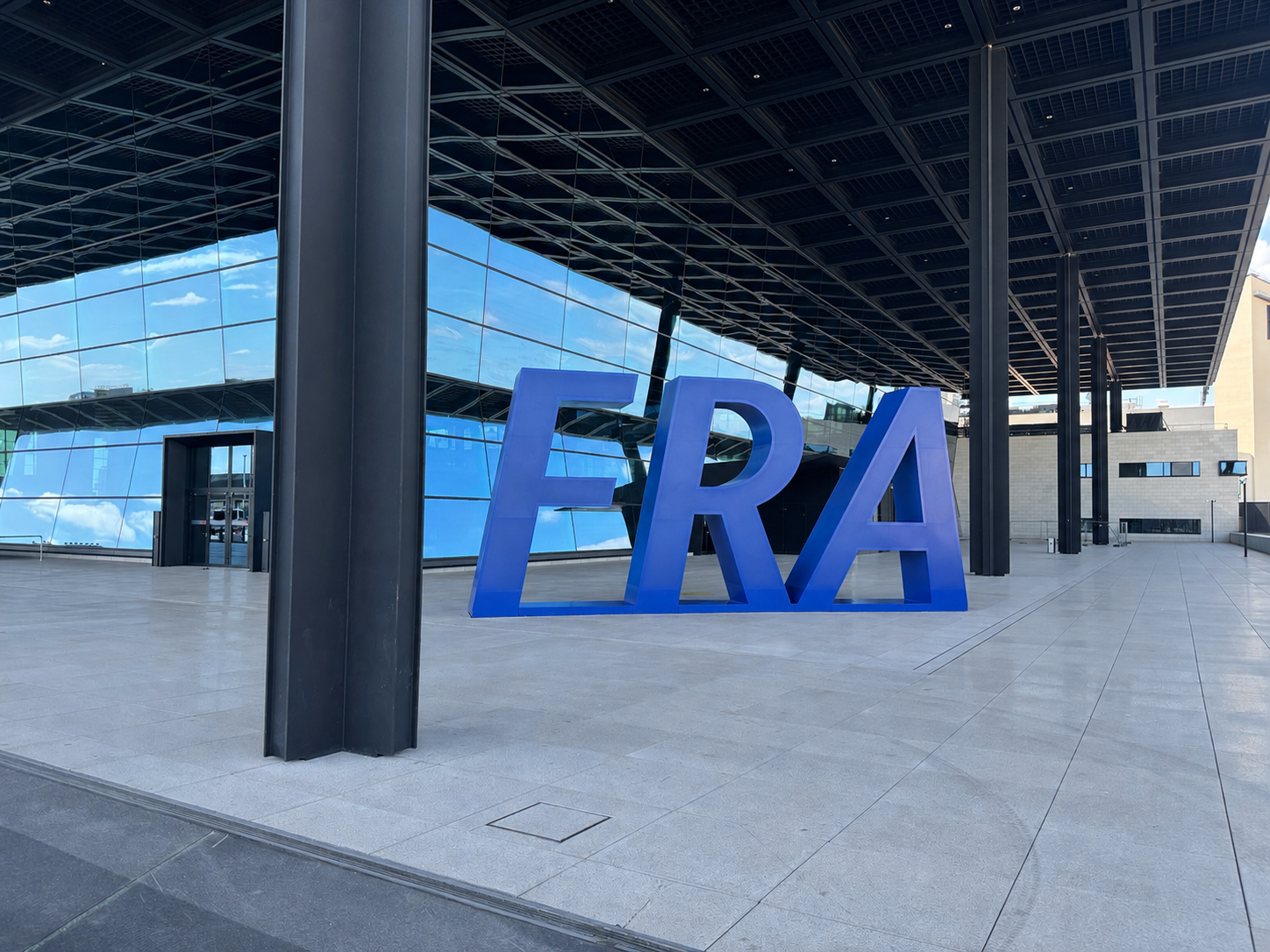 Blaue FRA-Skulptur am Eingang von Terminal 3 Flughafen Frankfurt mit verspiegelter Glasfassade